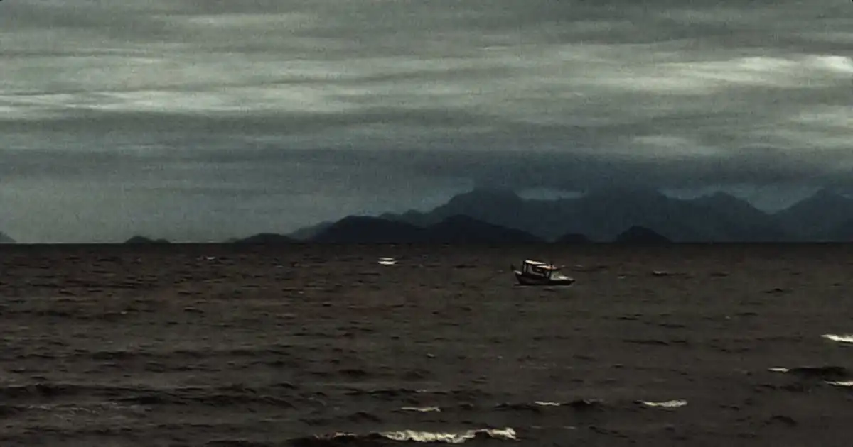 Foto de um barco solitário frente a uma tempestade em alto-mar.